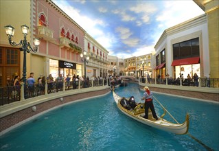 Gondolier in a Gondola with tourists in a replica of Venetian streets under an artificial sky