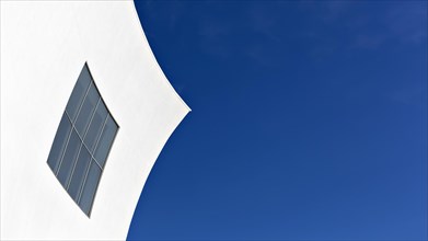 White concave facade with window against a blue sky