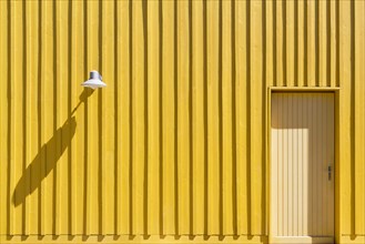Facade of a yellow beach hut with door and lamp
