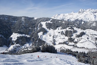 Skiers on slope in front of mountains