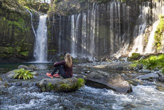 Young woman sitting on a stone in a river