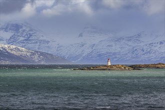 Lighthouse on the island Ytre Nortasholmen in front of snow covered mountains