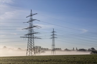 Electrical towers and power lines in the morning fog