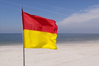 A red-yellow flag waves on the beach