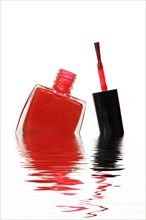 Red nail polish bottle with brush in water