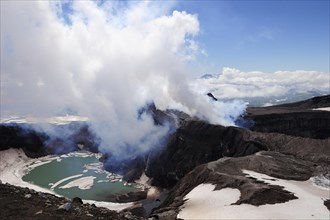 Volcanic crater with crater lake and a hot water vapour cloud