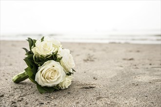 Bridal bouquet of white roses lying on a North Sea beach