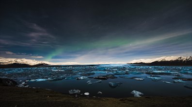 Chunks of ice in the water at the blue hour with polar lights