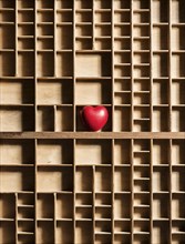 Red heart in empty wooden box with many compartments