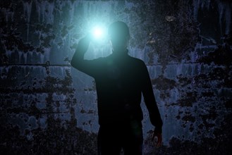 Man with flashlight in dark urban setting