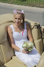 Bride posing in the back seat of an open car