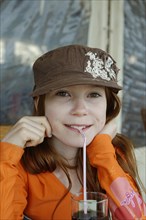 Girl with cap drinking with a straw