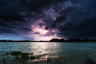 Storm clouds over a quarry lake with water plants