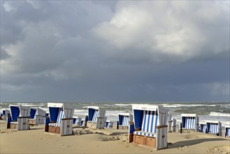 Beach of Westerland with white-blue beach chairs and rain clouds