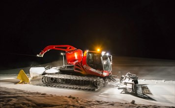 Snowcat planing ski slope with rope at night