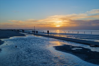 Beach walkers at the Wadden Sea on the North Sea coast in the blue hour at sunset