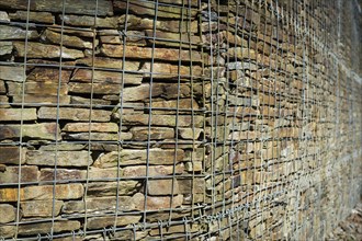Wall with stacked stones behind steel mesh