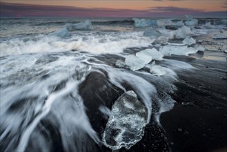 Blocks of ice on the black beach lapped by the sea