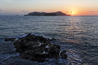 Sunrise next to small island in the sea
