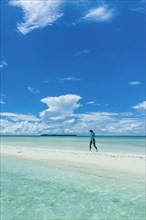 Tourist walking on a sand strip at low tide