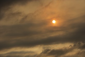 Sun behind clouds and brownish ash and gas clouds of the Holuhraun fissure eruption