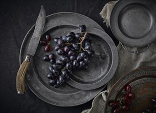 Pewter plates with grapes on a black underground