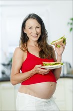 Pregnant woman holding sandwiches