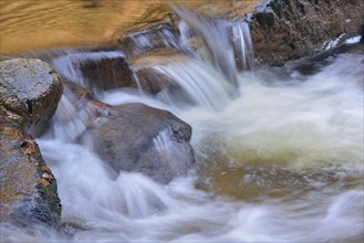 Water running over rocks in a brook in autumn