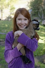 Girl holding a dwarf goat in the petting zoo at Schopperalm