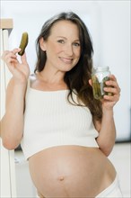 Pregnant woman holding a jar of pickled gherkins