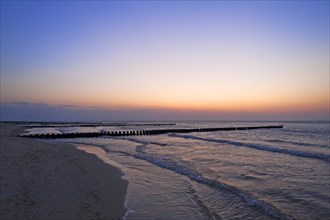 Groynes as coastal protection at the Baltic Sea beach with evening sky