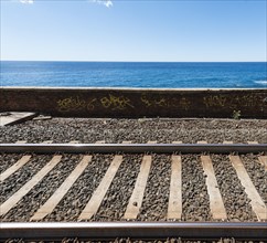 Railroad tracks in front wall with graffiti in front of the sea