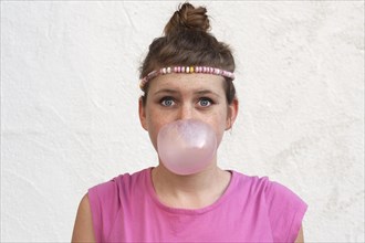 Teenage girl with a gum bubble in front of her face