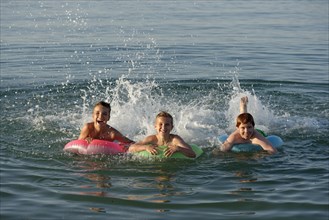 Children on floating tyres in the sea