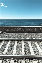 Railroad tracks in front wall with graffiti in front of the sea