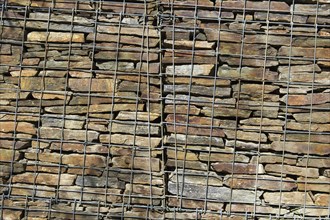 Wall with stacked stones behind steel mesh