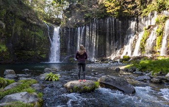 Young woman standing on a stone in a river