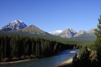 View of the Rocky Mountains across the Bow River and railway tracks