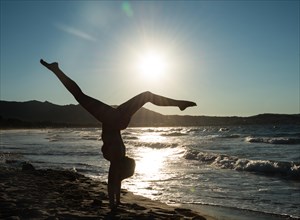 Young woman doing gymnastics on the beach