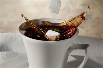 Sugar cubes falling into a cup of coffee