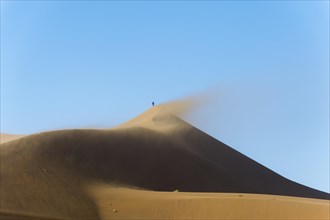 Hiker summits the peak of Big Daddy Dune