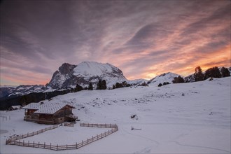 Sunrise over Mt Plattkofel and a mountain hut in winter