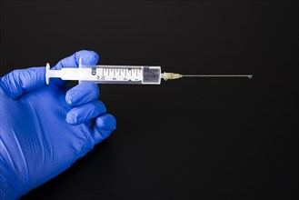 A hand with a blue medical glove is holding a syringe