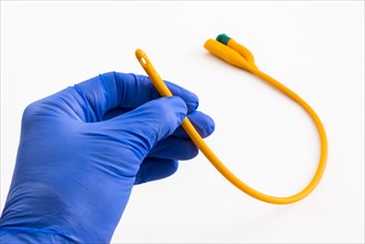 A hand with a blue medical glove is holding a balloon catheter