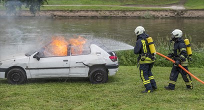Firefighters extinguish burning car