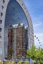 Statendam residential tower reflected in the glass facade of the market hall