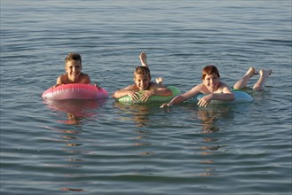 Children on floating tyres in the sea