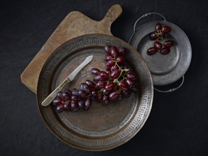 Pewter plates with grapes on a black underground