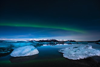 Chunks of ice in the water at the blue hour with polar lights