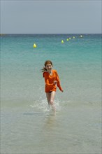 Girl running through the turquoise waters of the Bay of Rondinara